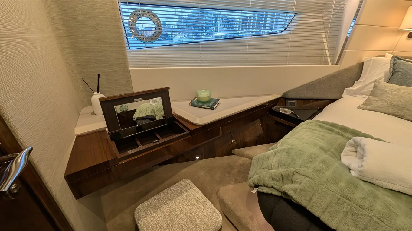 Stylish bedroom featuring a double bed, olive throw, decorative vase, and an elegant storage unit with a mirror.